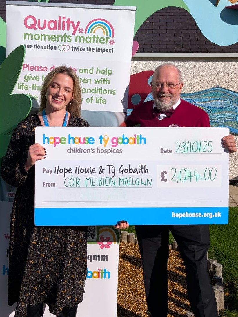 A member of the Choir stood holding a large cheque for Hope House Children's Hospices.