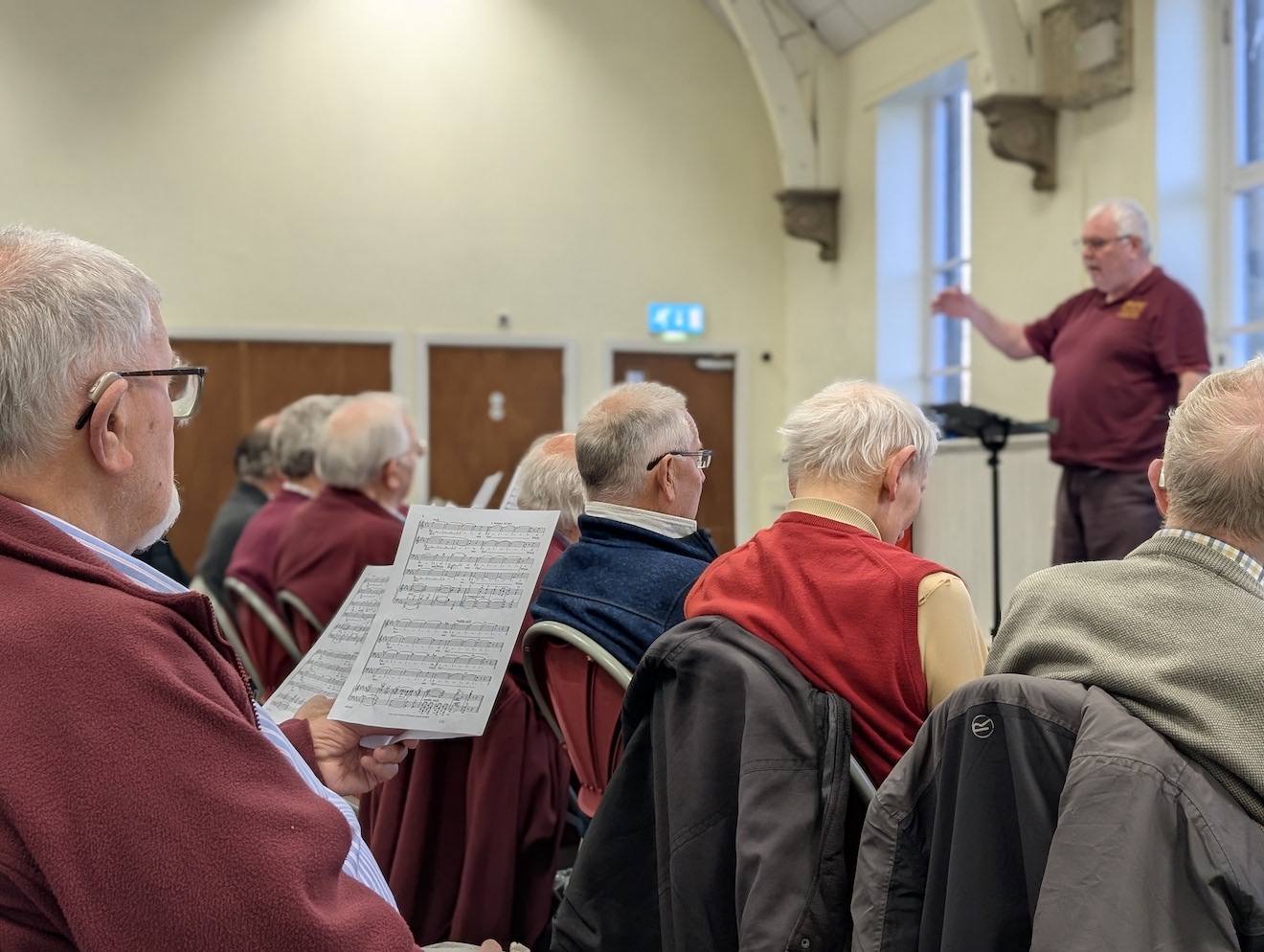 07:Choir rehearsal with the Musical Director at the front. Photo is a close up.