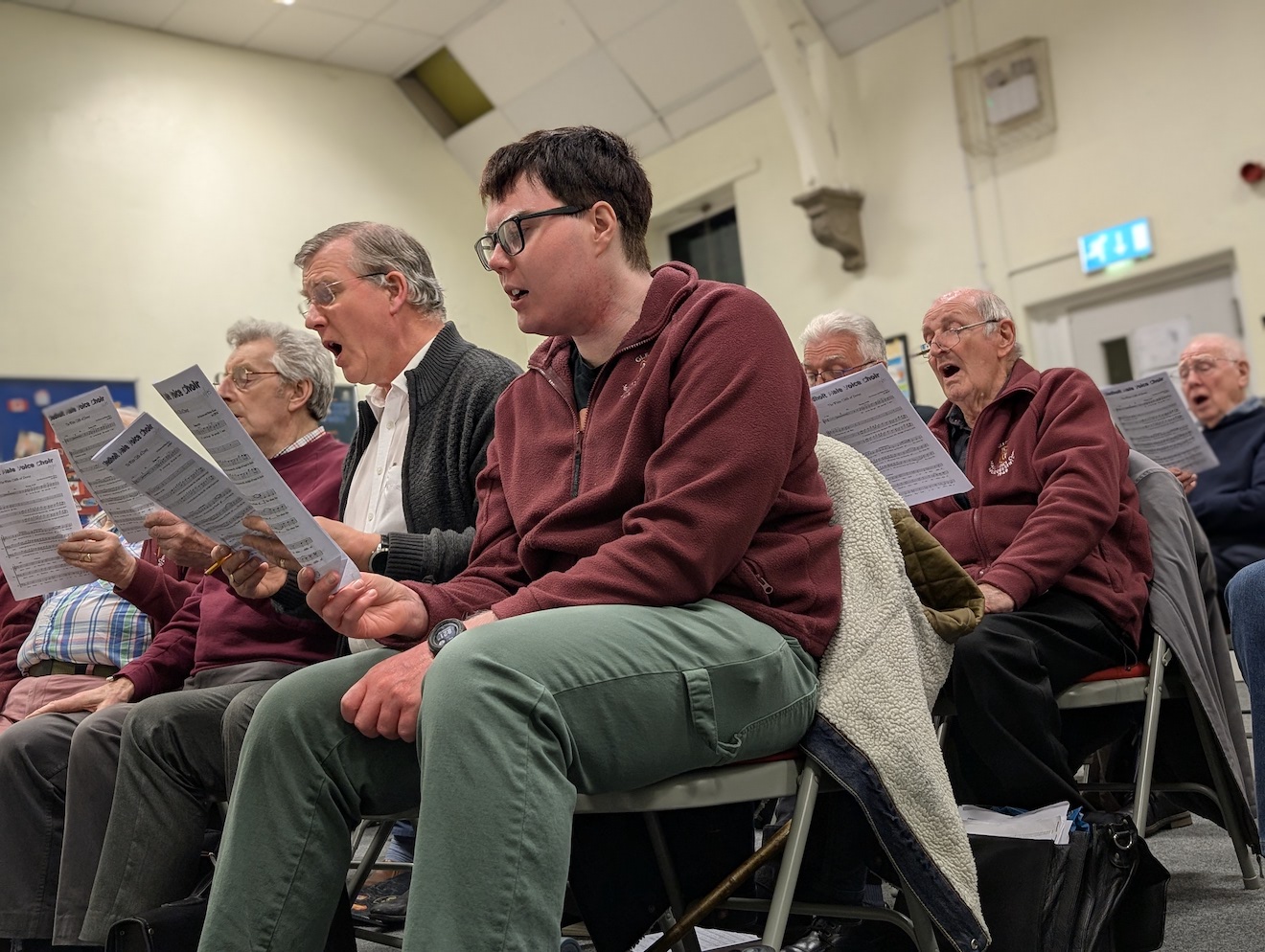 34:Choir rehearsal. Photo is a close up of choir members reading their music sheets.