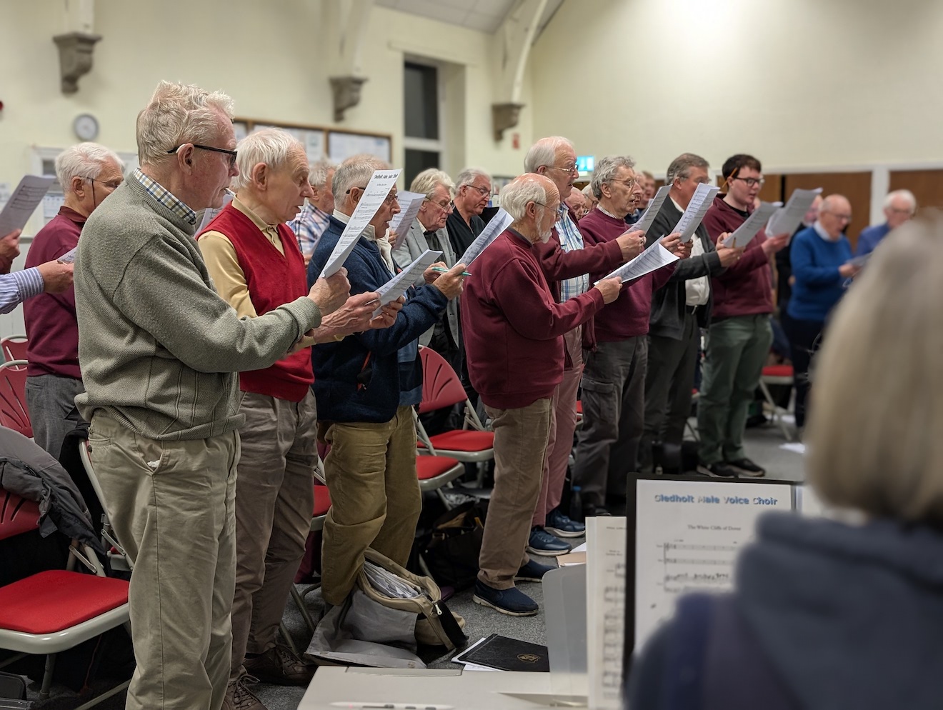 39:Choir rehearsal. Photo is a close up of choir members taken from behind the Accompanist.