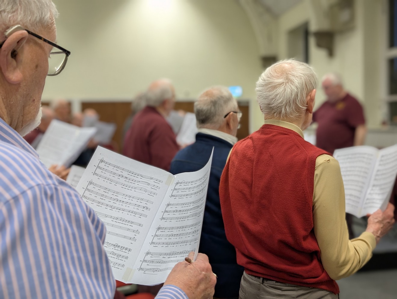 41:Choir rehearsal. Photo is a close up of choir members reading their music sheets.