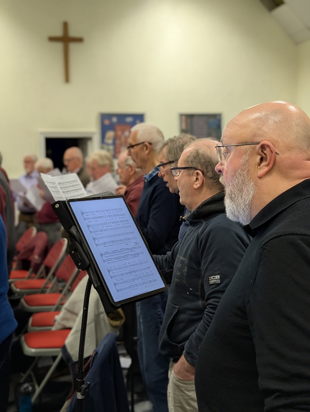 47:Choir rehearsal. Photo is a close up of choir members reading their music sheets.