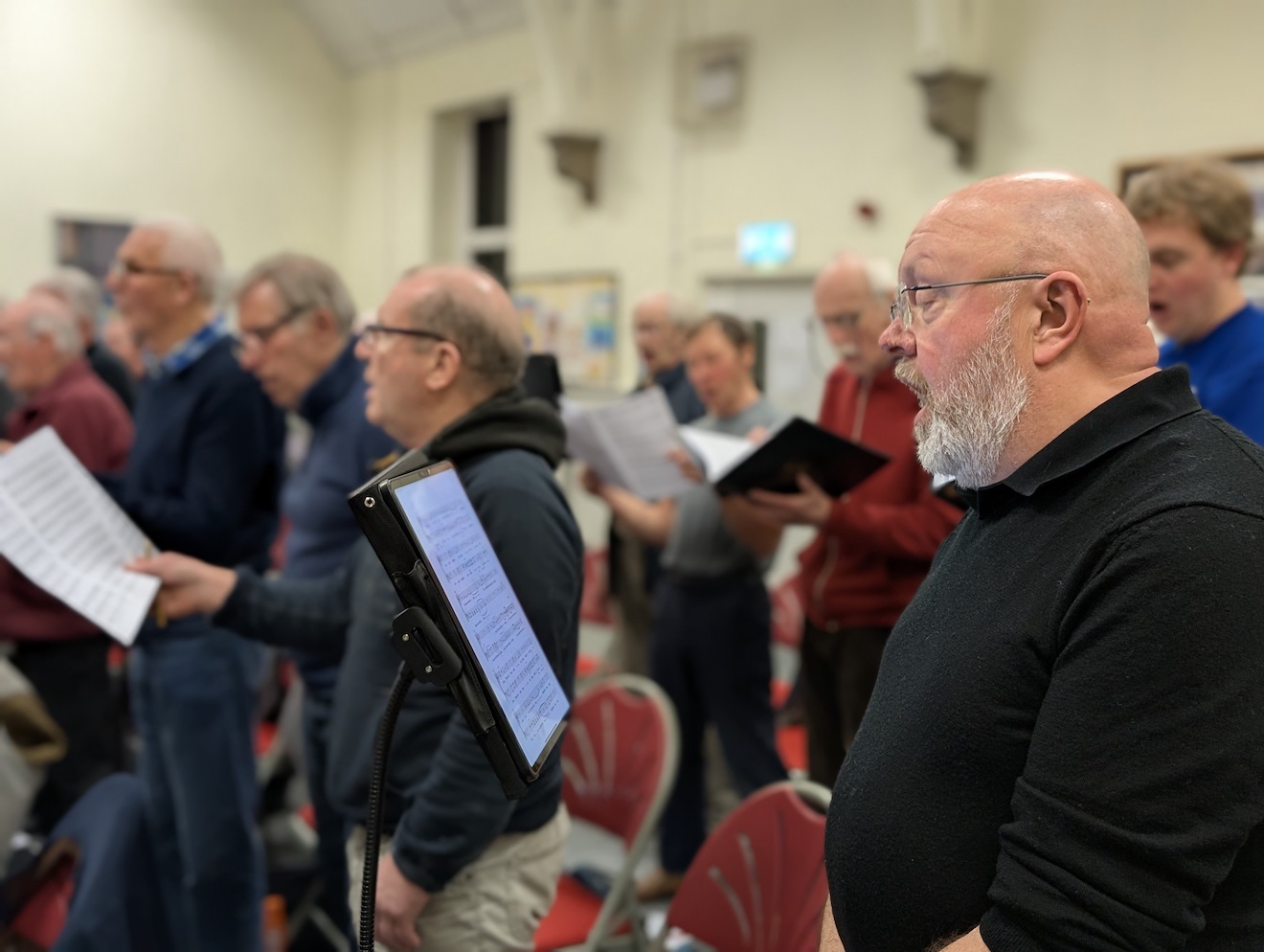 52:Choir rehearsal. Photo is a close up of choir members reading their music sheets.
