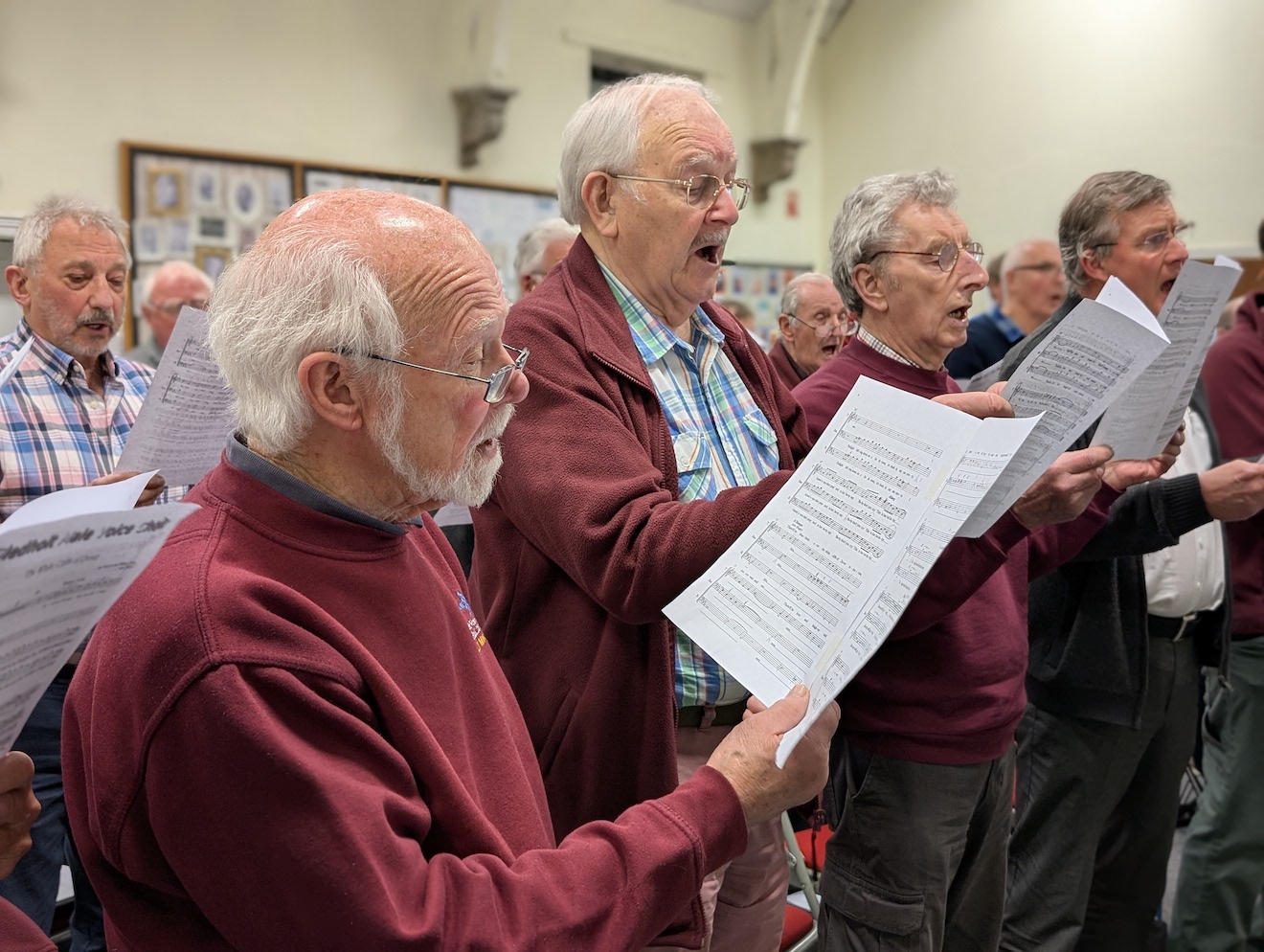 56:Choir rehearsal. Photo is a close up of choir members reading their music sheets.